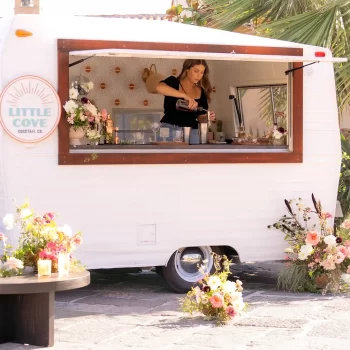 A person pouring drinks out of a retro trailer.